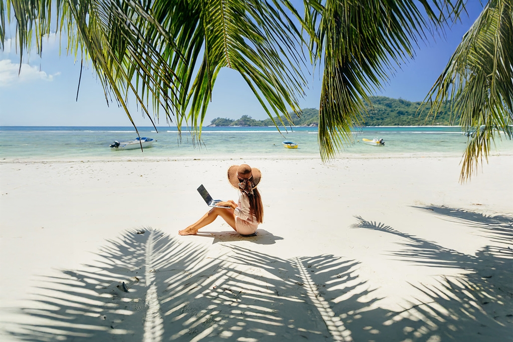 A woman on a lap top on a beach
